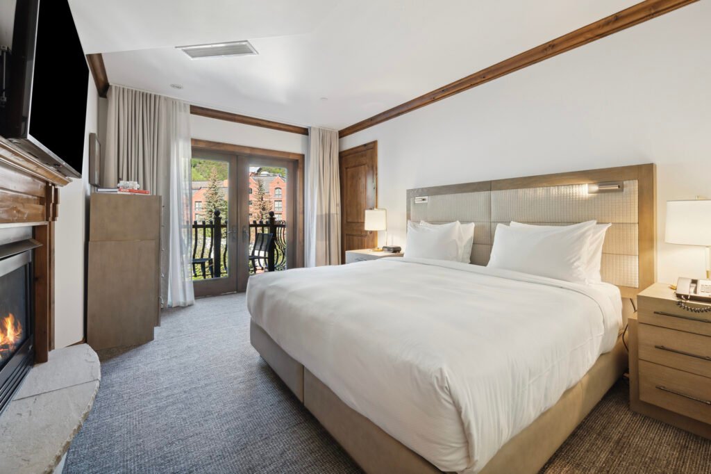 Finished bedroom at Aspen Mountain Residences with wood trim, king bed and balcony doors.