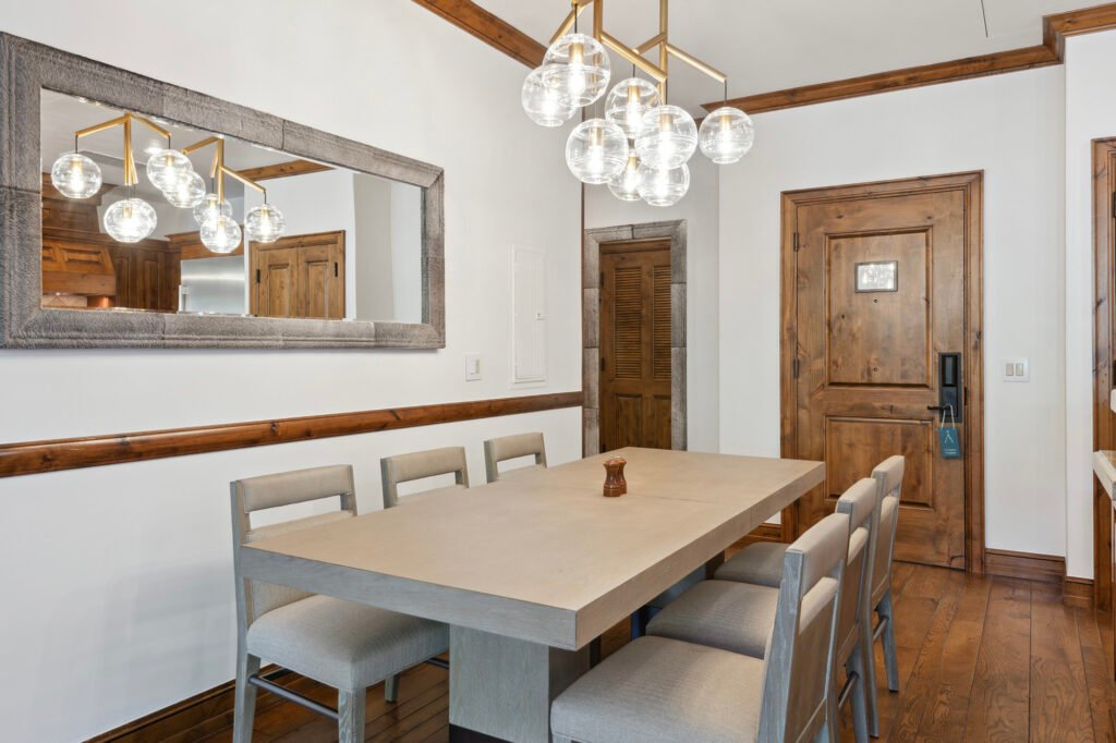 Finished dining area at Aspen Mountain Residences with light wood table and glass pendant lights.