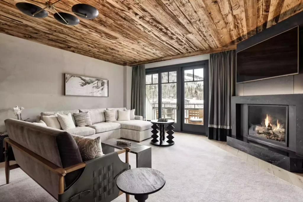 Renovated Four Seasons Vail suite with wood ceiling, stone fireplace, and mountain-facing balcony