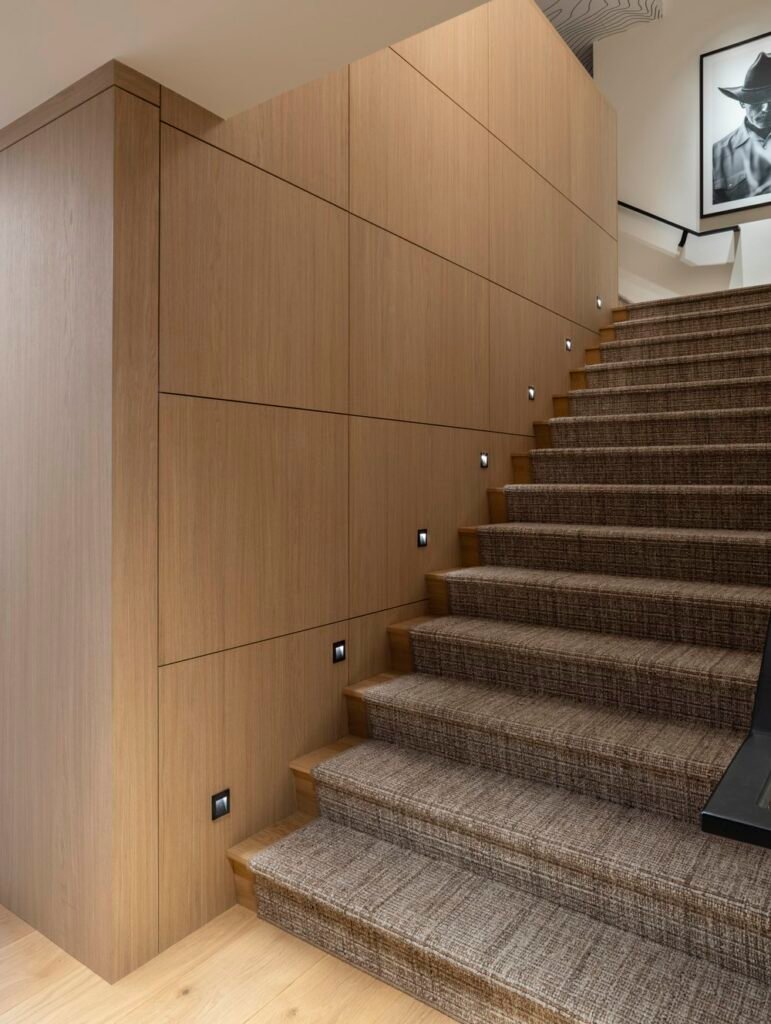 Renovated Paris penthouse stair with custom wood paneling and integrated step lighting