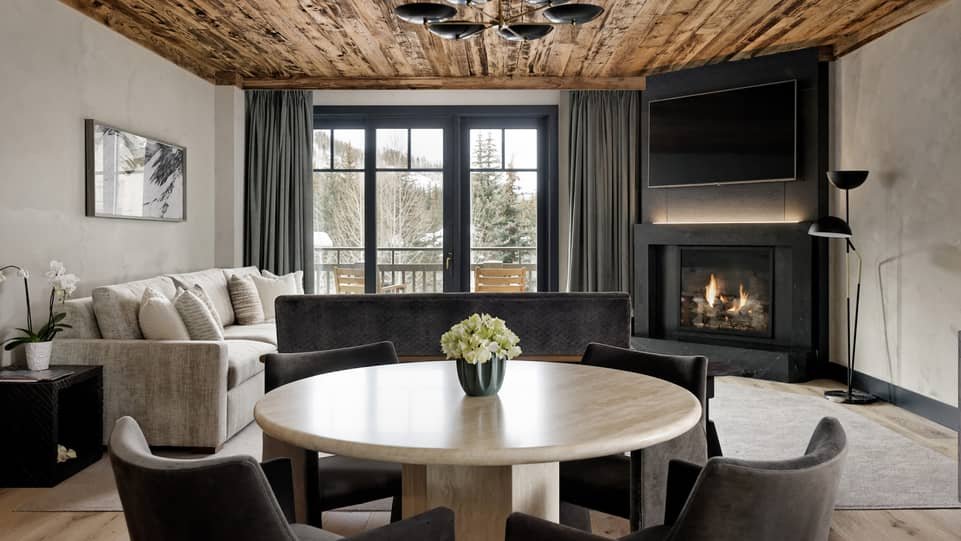 Renovated Four Seasons Vail suite dining area with wood ceiling, lounge seating, and fireplace