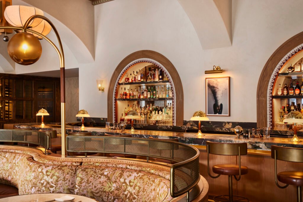 Completed Tavernetta Vail bar with arched bottle displays, stone counter, and curved banquette seating